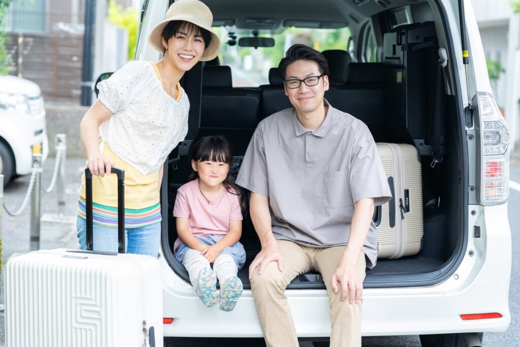 レンタカーに荷物を積み込む家族